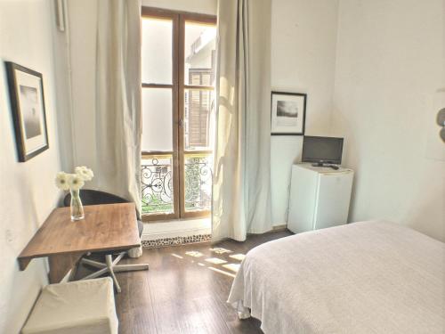 een slaapkamer met een bed, een bureau en een raam bij Villa Saint Charles in Juan-les-Pins