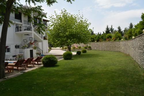 a garden with a stone wall and tables and chairs at Hotel Aroma in Përmet
