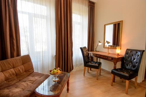 a living room with a couch and a table and a desk at Hotel British House in Tbilisi City