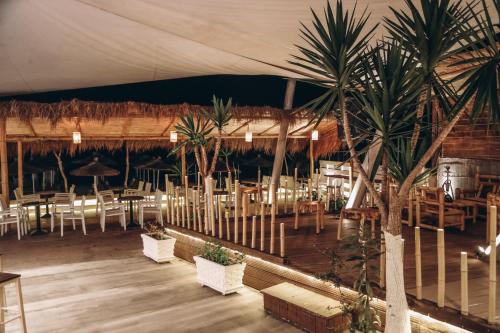 a restaurant with palm trees and tables and chairs at Hotel Aloha in Sarandë