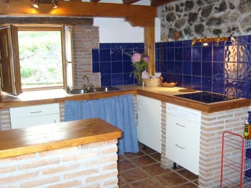 cocina con azulejos azules en las paredes y fregadero en La casita de las flores, en Monte Miravalles