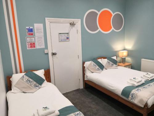グレート・ヤーマスにあるCavendish House Hotelのオレンジと白のオーブが壁に施された客室で、ベッド2台が備わります。
