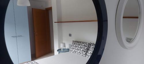 1 dormitorio con espejo y 1 cama con silla en Villa Luigi a Poggio dei Pini, alloggio con giardino e posto auto, en Capoterra