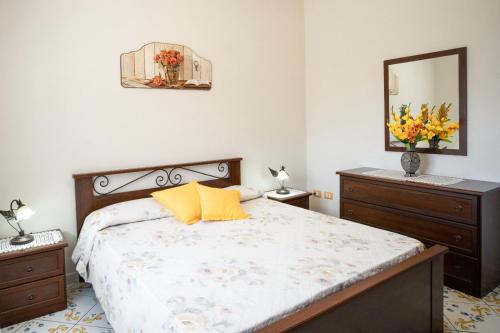 una camera da letto con letto, cuscini gialli e specchio di Casa Vacanza La Gardenia a Tramonti