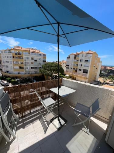 une table et des chaises sur un balcon avec un parasol dans l'établissement Superbe appartement à Proximité Plage et Port, au Cap d'Agde