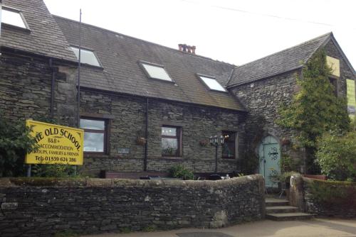 an old stone house with a yellow sign in front of it at The Old School B&B in Tebay