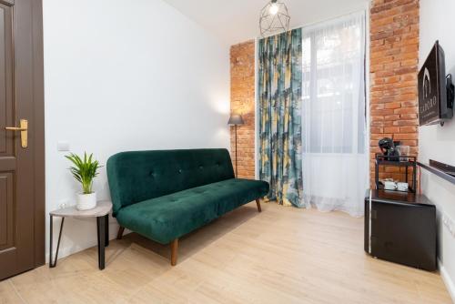 um sofá verde numa sala de estar com uma parede de tijolos em CADORO City Center Apartments em Oradea