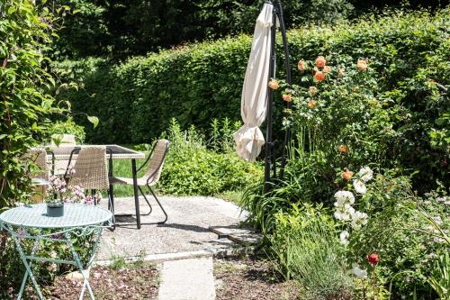 eine Terrasse mit einem Tisch und einem Sonnenschirm in einem Garten in der Unterkunft OMA's Apartment in Haus GRETE in Bad Waltersdorf