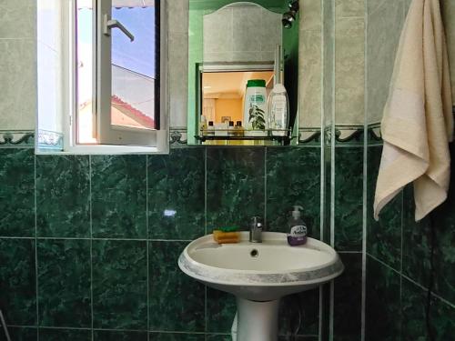 a green tiled bathroom with a sink and a mirror at La Casa de Habel in Quba