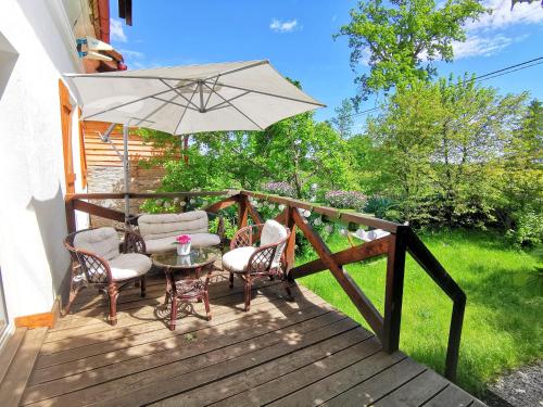 a patio with a table and chairs and an umbrella at Leszczynowy Sad - apartament z kominkiem i ogrodem in Wydminy