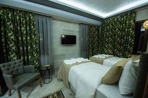 a hotel room with two beds and a chair at Ahiyan Hotel in Uchisar