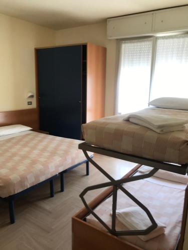 a bedroom with two beds and a table and a window at Hotel Soave in Cervia