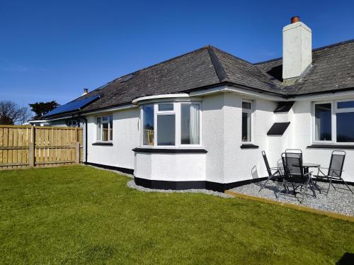 a white house with a table and chairs in a yard at Trevose, sea views in Port Isaac