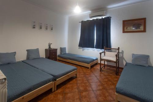 a room with two beds and a chair and a window at Vivenda Esgravina in Sesimbra