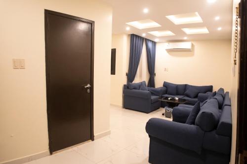 a living room with blue couches and a black door at شقق أمواج للشقق المخدومة in Al Khobar