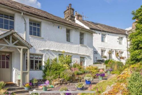 a white house with a garden in front of it at The Old Post Office, Cosy Grade II listed 2 bed apartment Windermere in Windermere