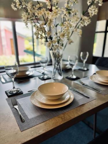 a table with plates and glasses and a vase with flowers at The Old Post Office, Cosy Grade II listed 2 bed apartment Windermere in Windermere