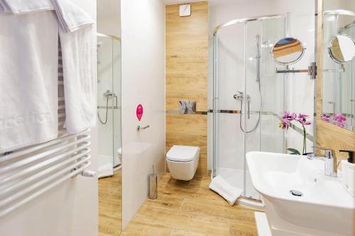 a bathroom with a shower and a sink and a toilet at VacationClub - Rezydencja Karkonoska Apartament 10 in Karpacz
