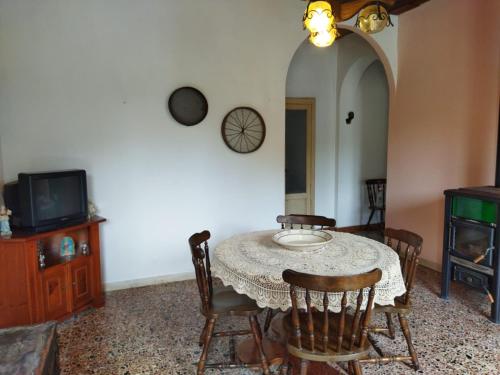 een eetkamer met een tafel en stoelen en een tv bij La casa di Donna Ciccina in Bovalino Superiore