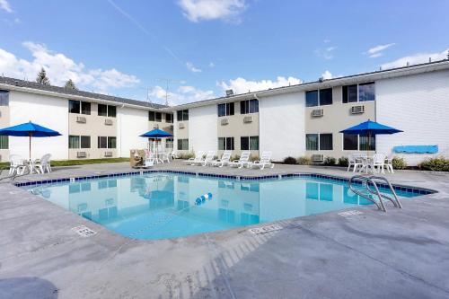 a pool in front of a hotel with chairs and umbrellas at Econo Lodge in Idaho Falls