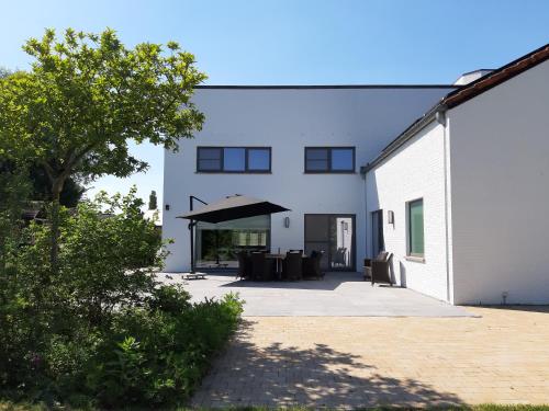a white building with a patio in front of it at Ruime woning met grote omheinde tuin in Hasselt
