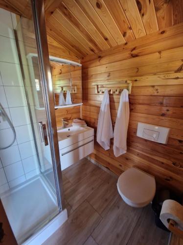 a wooden bathroom with a shower and a toilet at WIR Gąski - domki letniskowe in Gąski