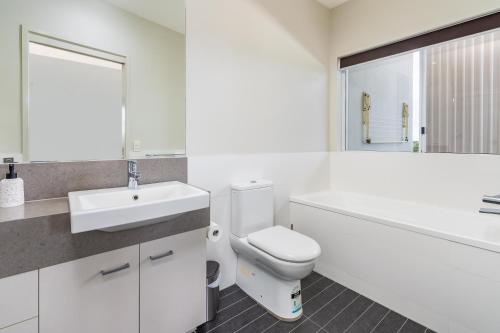 a white bathroom with a toilet and a sink at Keith's on Pumicestone, 1 of the 3 most popular units on Bribie in Bongaree