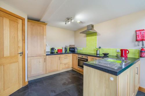 a kitchen with wooden cabinets and a black counter top at The New Chapel in Goxhill
