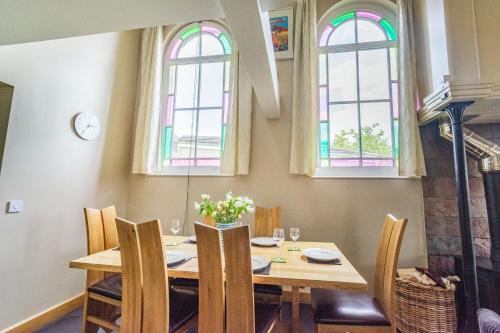 a dining room with a table and two windows at The New Chapel in Goxhill