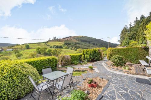 a patio with a table and chairs and a hill at Henrhiw Bach in Dolwyddelan