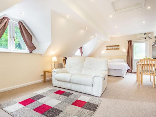 uma sala de estar com um sofá branco e uma cama em Beeches Studio em Great Witcombe