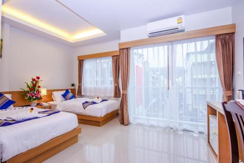 a bedroom with two beds and a large window at PKL Residence in Patong Beach