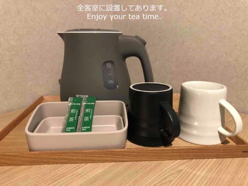 a tea pot and cups on a wooden shelf at Henn na Hotel Kanazawa Korimbo in Kanazawa