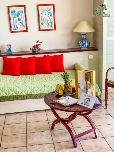 a room with a bed with red pillows and a table at Hotel Auberge de la Vieille Tour in Le Gosier