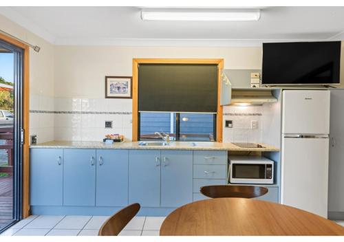a kitchen with blue cabinets and a wooden table at Discovery Parks - Mackay in Mackay