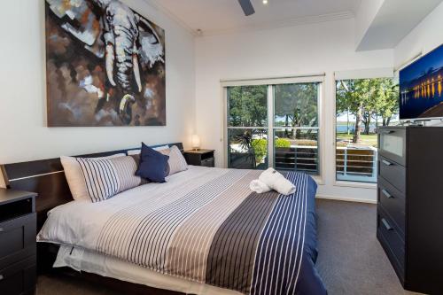 a bedroom with a bed and a large window at Keith's on Sylvan Beach, 1 of the 4 most popular units on Bribie in Bellara