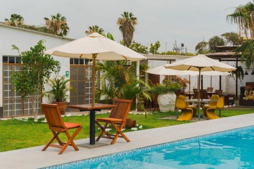 un patio con sillas, mesas y sombrillas junto a una piscina en Hermosa Casa de Campo con Piscina grande en Chiclayo, en Ferreñafe