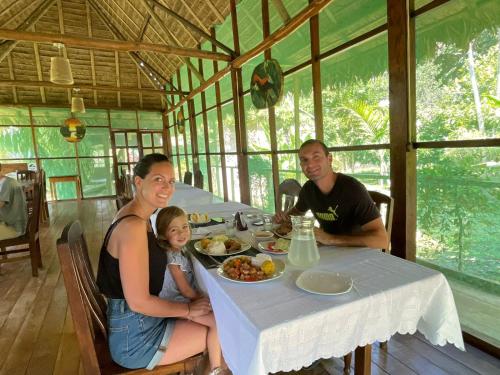 a family sitting at a table with a plate of food at Estancia Bello Horizonte in Puerto Maldonado