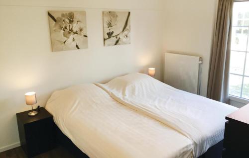 een slaapkamer met een bed met witte lakens en een raam bij Buitengoed Het Lageveld - 84 in Hoge-Hexel