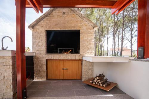 an outdoor kitchen with a fireplace in a stone building at Villa Kalinić in Milna