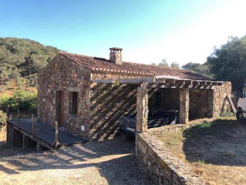 an old stone house with a porch in a field at Casas de Campo do Castro da Cola in Marchicão