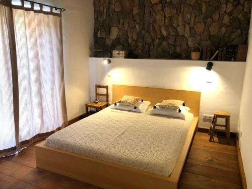 a bedroom with a large bed and a large window at Casas de Campo do Castro da Cola in Marchicão