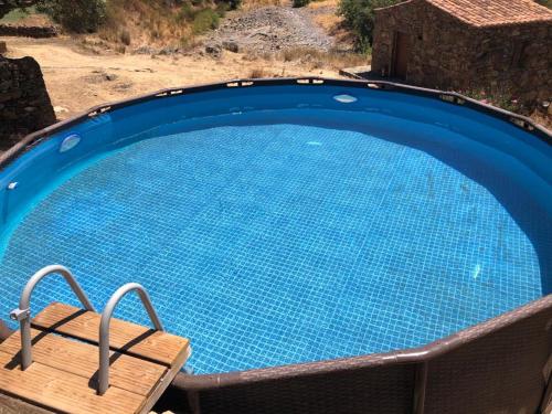 a large blue swimming pool with a wooden bench around it at Casas de Campo do Castro da Cola in Marchicão