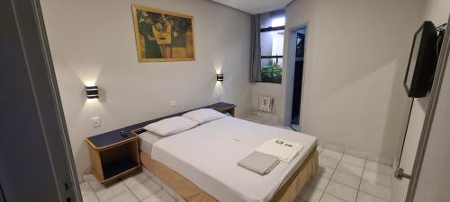 una piccola camera da letto con un letto e una televisione di Giardino Hotel a Itaquaquecetuba