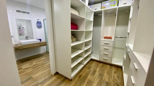 a walk in closet with white cabinets and a sink at Moderna y Unica casa independiente con jardín y estacionamiento in Ciudad del Este