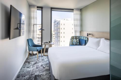 a hotel room with a white bed and a chair at Holiday Inn Express Auckland City Centre by IHG in Auckland