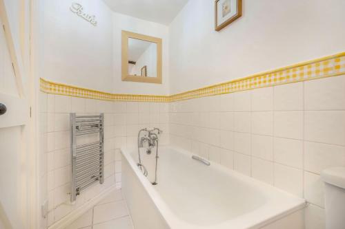 a white bathroom with a tub and a sink at Lavender Cottage in Askrigg