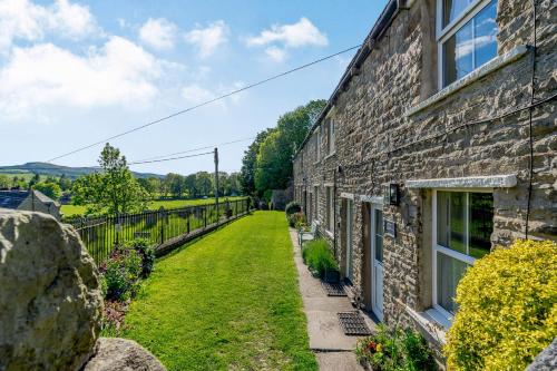 an old stone house with a garden next to a building at Lavender Cottage in Askrigg