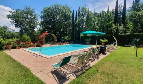 a swimming pool with chairs and an umbrella at Torre Del Cielo in Monterchi