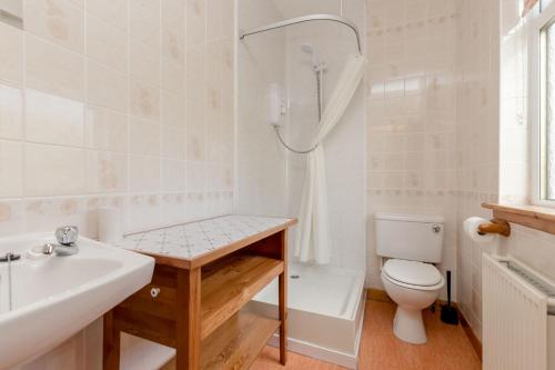a bathroom with a sink and a toilet and a tub at Foxglove Cottage in Maybole